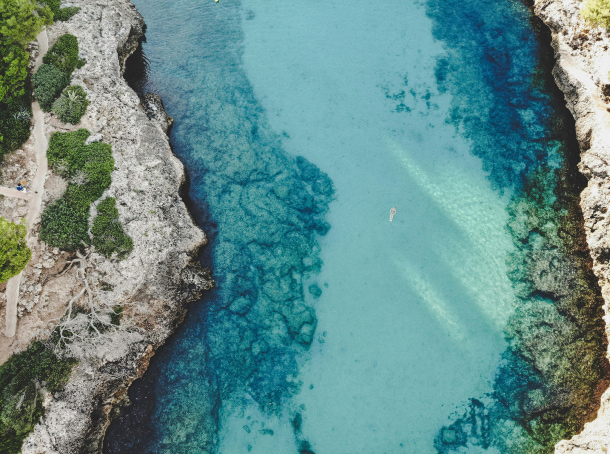 Mujer nadando en una cal de aguas cristalinas en el sur de mallorca