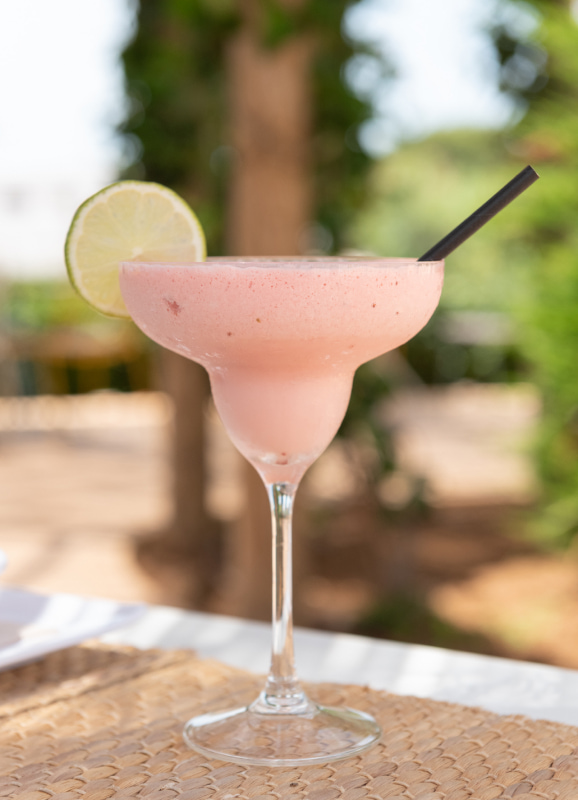 Refrescante cóctel rosa en copa alta, decorado con una rodaja de lima en el borde.