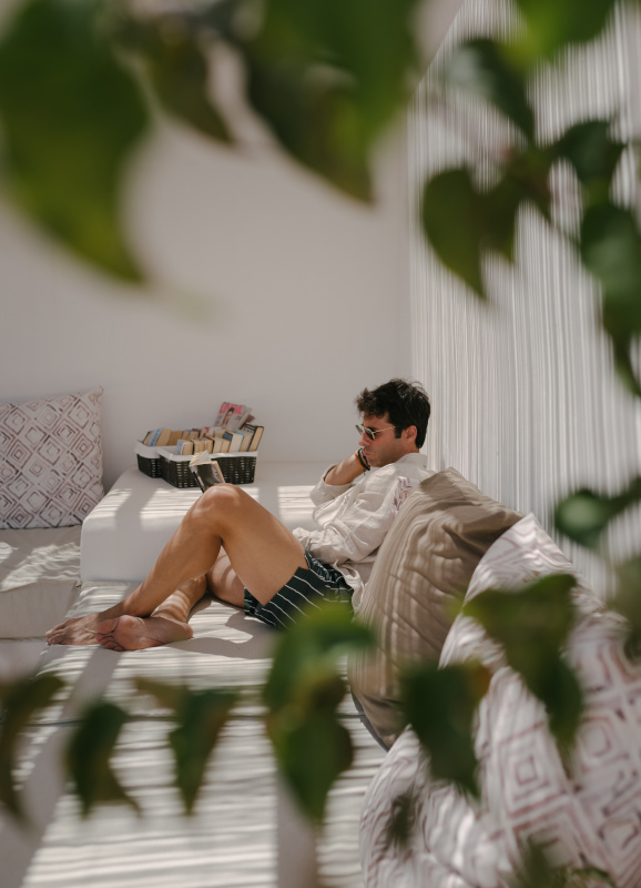 Guest of Eques Petit Resort reading in one of the outdoor chill out areas with cushions.