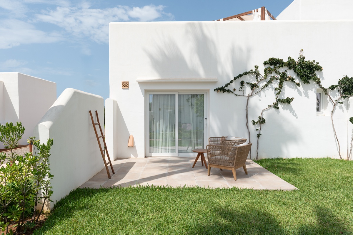 Terraza con sillas de mimbre y rodeada de jardines