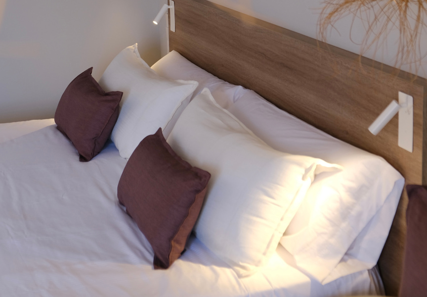 Detail of the pillows on the bed, in white and brown colours.